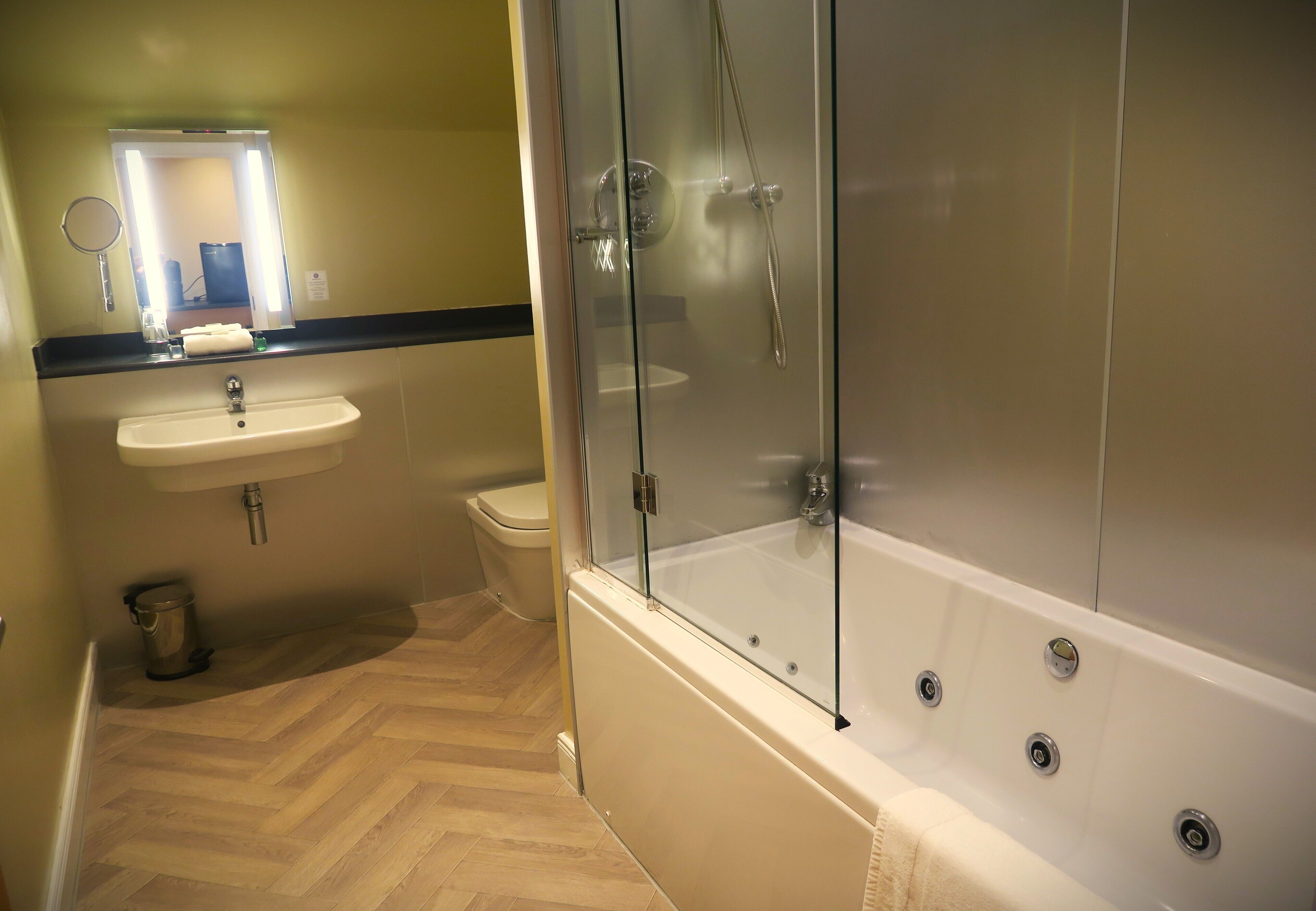 A bathroom with a glass-enclosed shower, a sink, and a toilet.