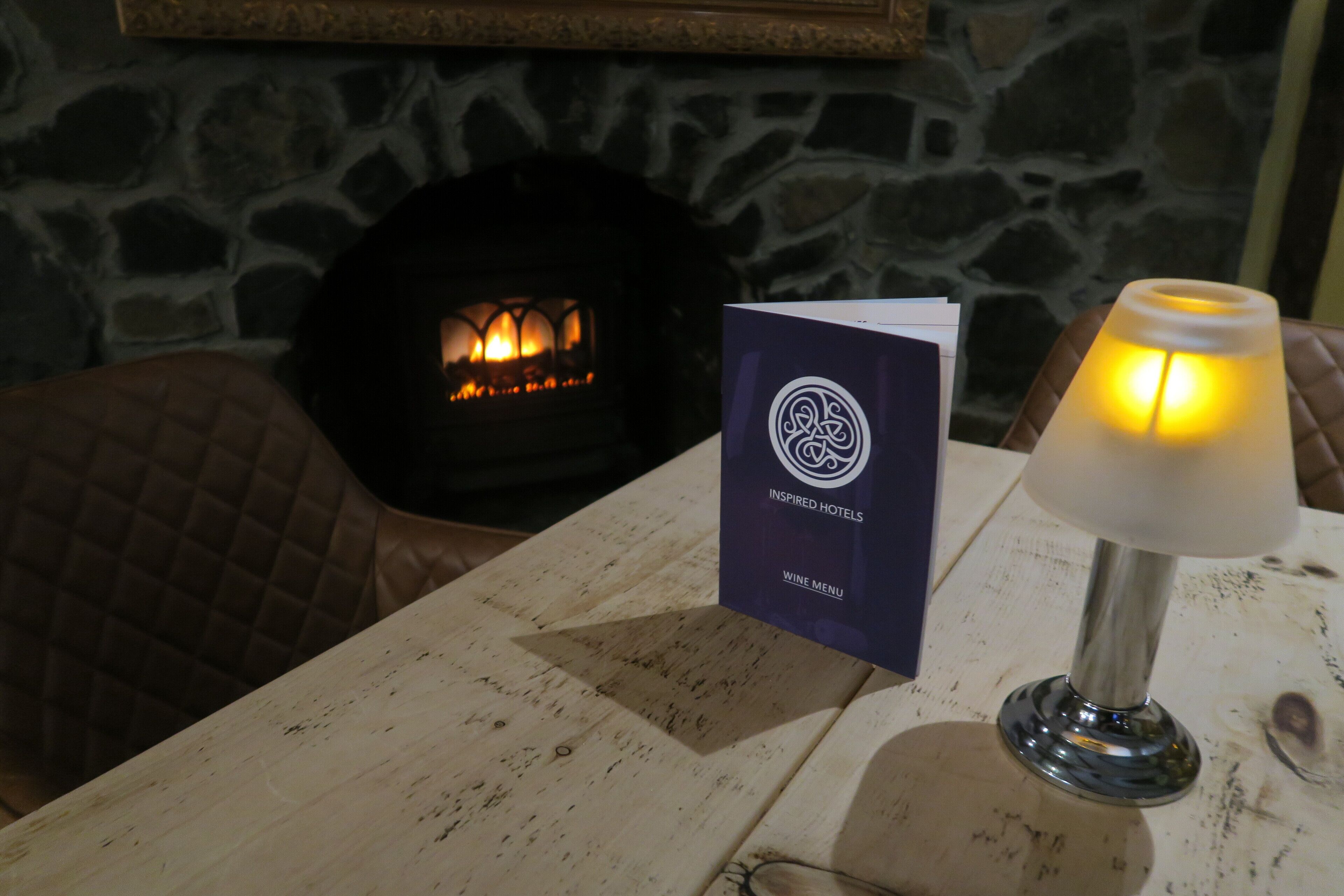 A table with a brochure titled "Inspired Hotels" and a lit table lamp.