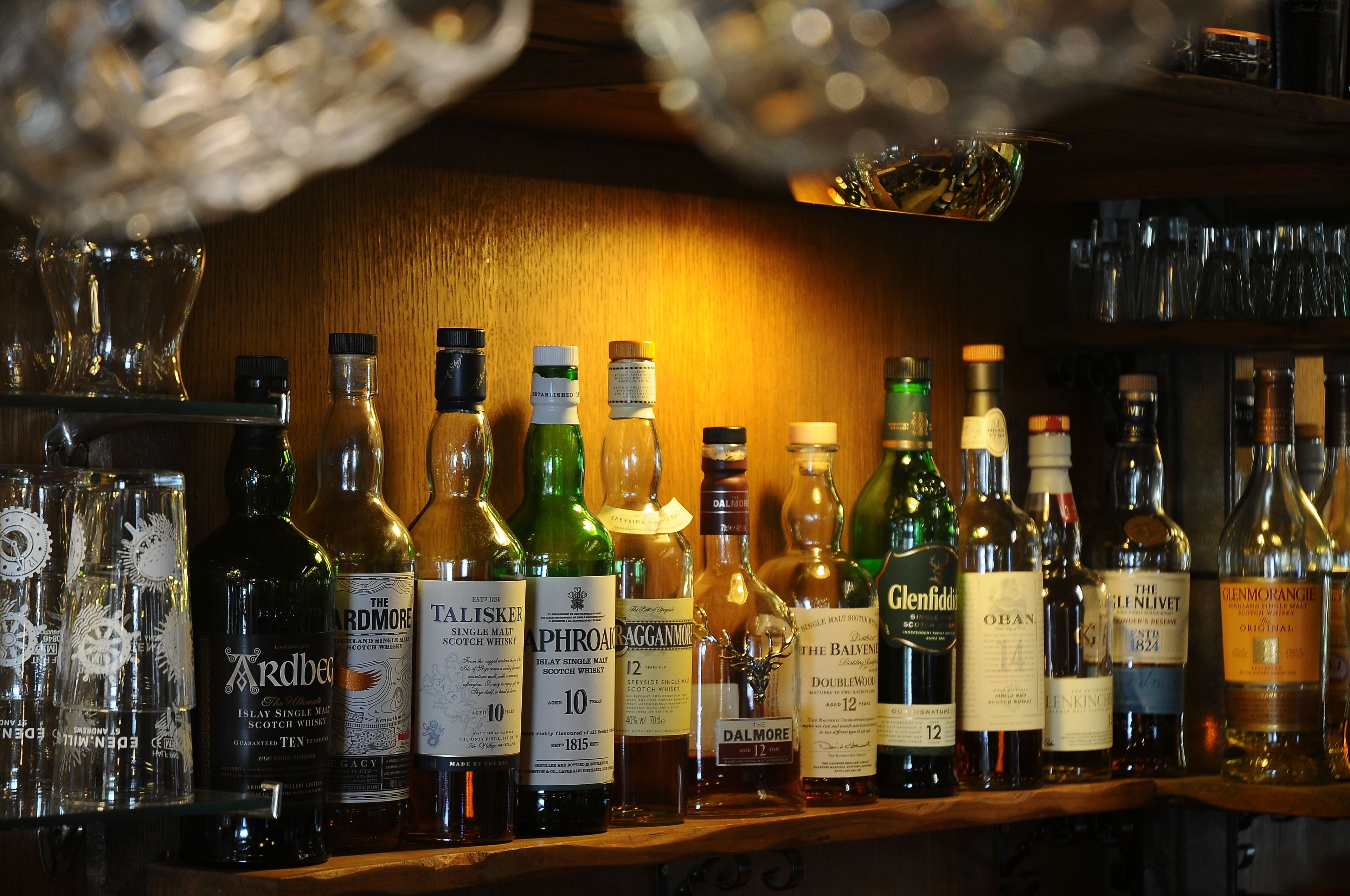 A variety of liquor bottles on a shelf, including brands like Ardbeard, Talisker, and Glenfiddich.