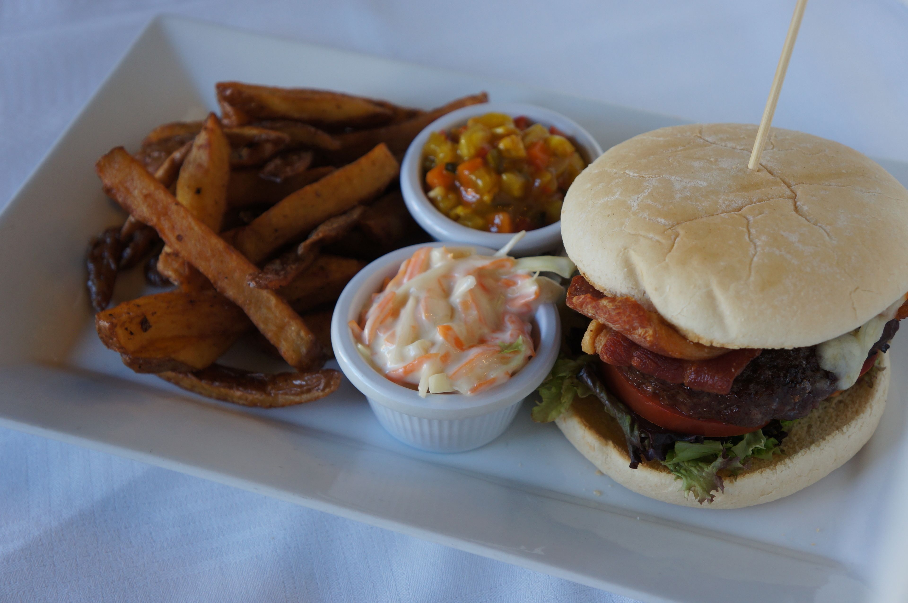 Una comida que incluye una hamburguesa, papas fritas y dos acompañamientos.