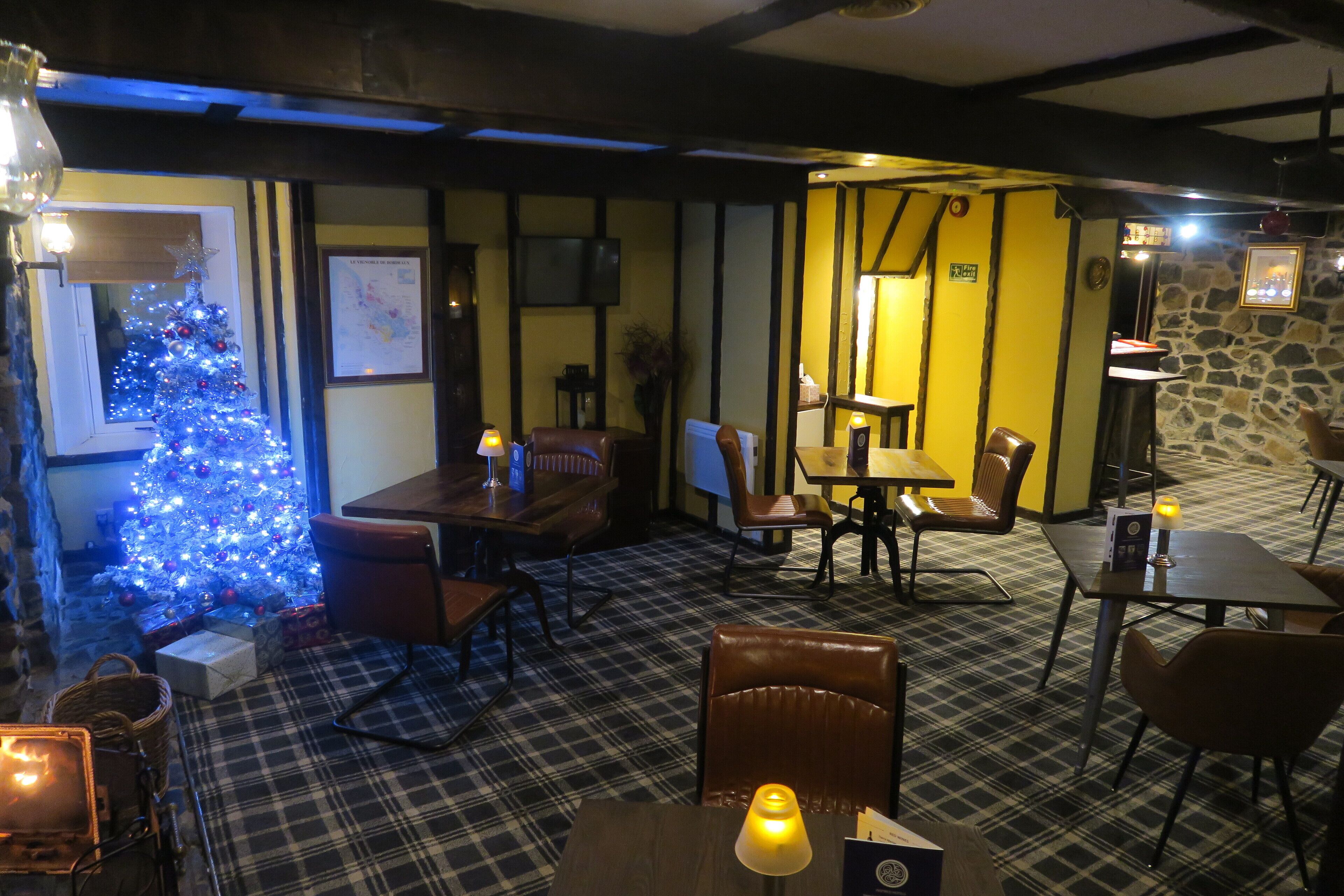 Un accogliente ristorante con un albero di Natale, pavimento a quadri e arredi in legno.