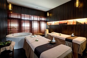 A spa room with two massage tables, a large bathtub, and wooden paneling. - Centara Villas Samui (Koh Samui)
