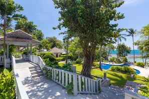A wooden deck with white railings leading to a gazebo, surrounded by lush greenery and a view of the ocean. - Centara Villas Samui (Koh Samui)