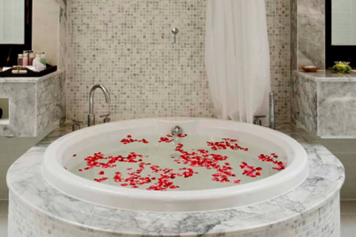 A bathroom with a freestanding bathtub, a shower, and a tiled wall.