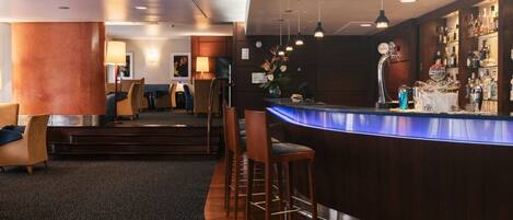 A modern bar area with a curved counter, bar stools, and a well-stocked liquor cabinet.