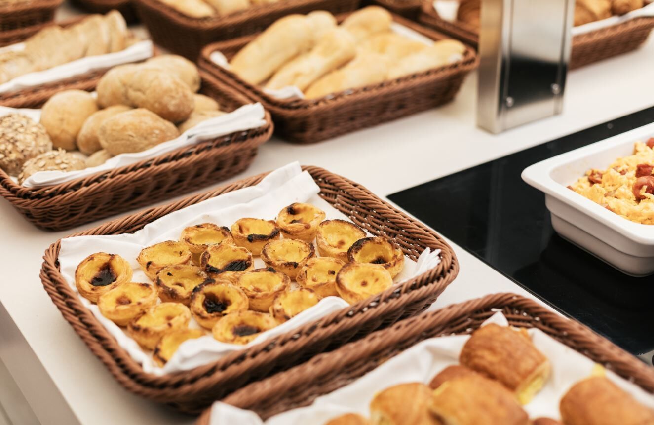 Buffet com diversas opções de pães, doces e bolachas.