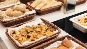 Buffet com diversas opções de pães, doces e bolachas.