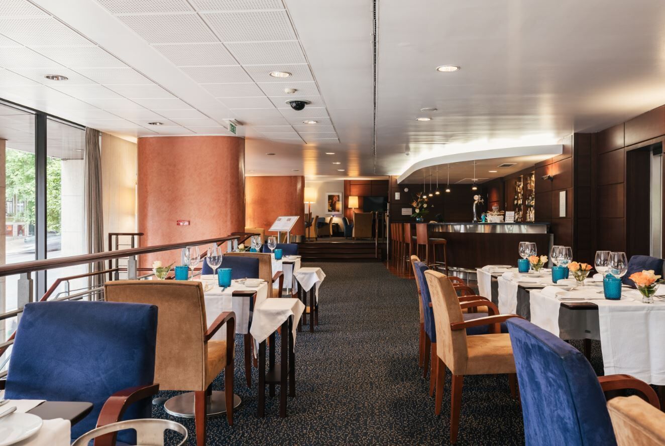 A restaurant with tables set for dining, a bar area, and a staircase leading to an upper level.