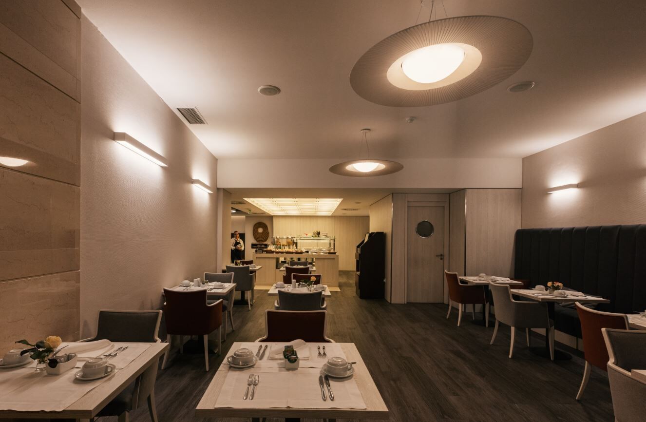 A restaurant with tables set for dining, a bar area, and a kitchen in the background.