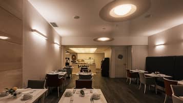 A restaurant with tables set for dining, a bar area, and a kitchen in the background.