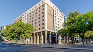 Un hôtel à plusieurs étages, doté d’une entrée imposante et offrant une vue dégagée sur le ciel.