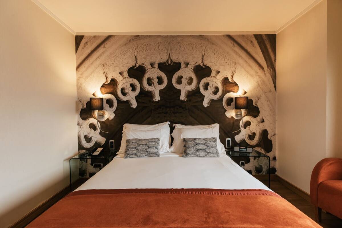 Une chambre à coucher avec un grand lit, une tête de lit décorative et des lampes de chevet.