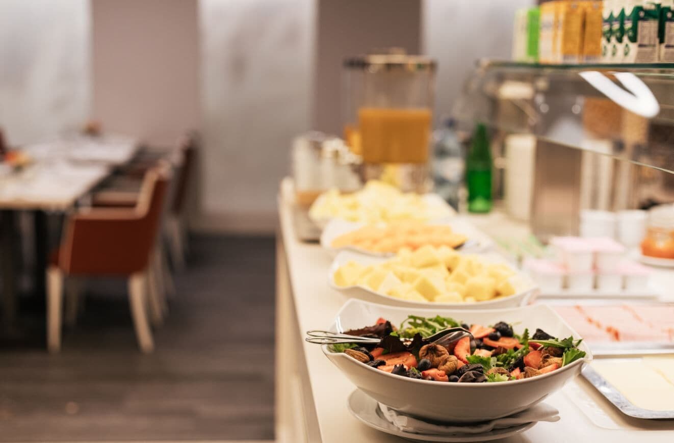 A buffet with various food items including salads, fruits, and beverages.