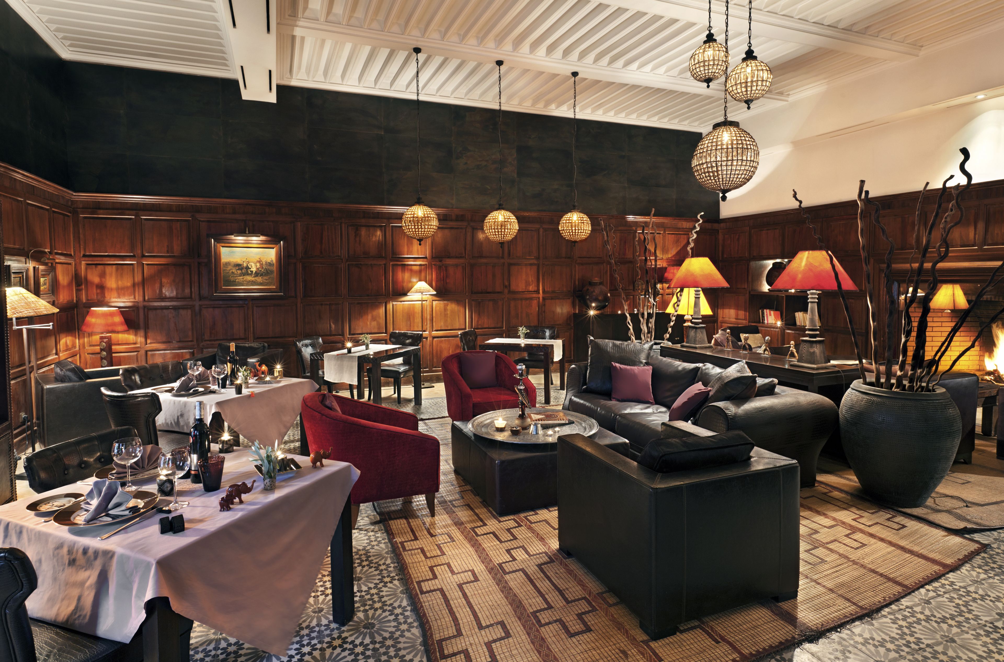 A spacious lounge area with a high ceiling, wooden paneling, and a variety of seating options including sofas and armchairs.