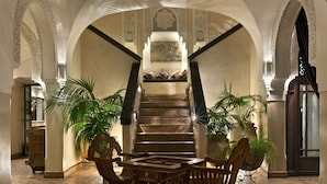 A grand staircase with intricate arches and a view of a room with a bed and a large window. - La Villa Des Orangers - Relais & Châteaux (Marrakech)