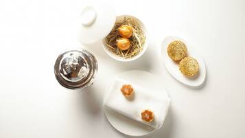 A white table with a glass of water, a bowl of eggs, and two plates of cookies.