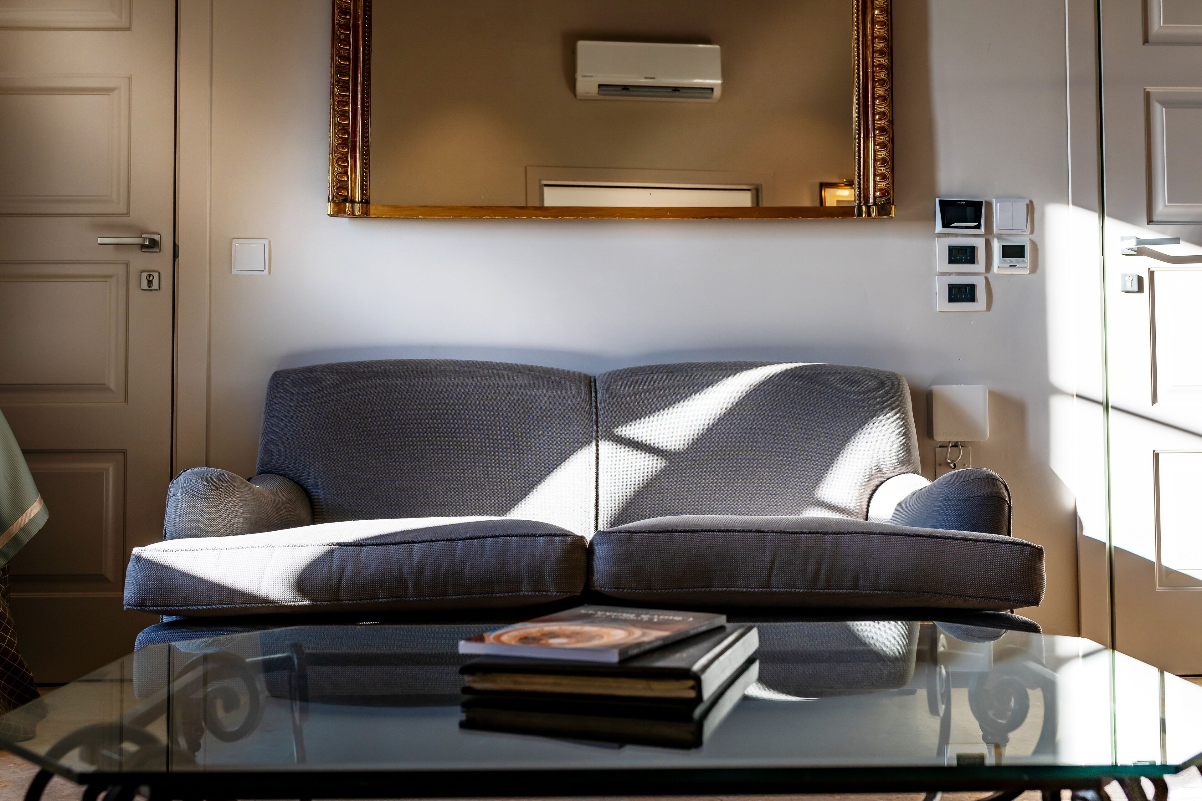 A modern living room with a grey sofa, a glass coffee table, and a book.