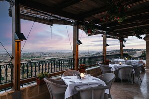 Une terrasse avec des tables dressées pour le repas, offrant une vue sur un paysage magnifique.