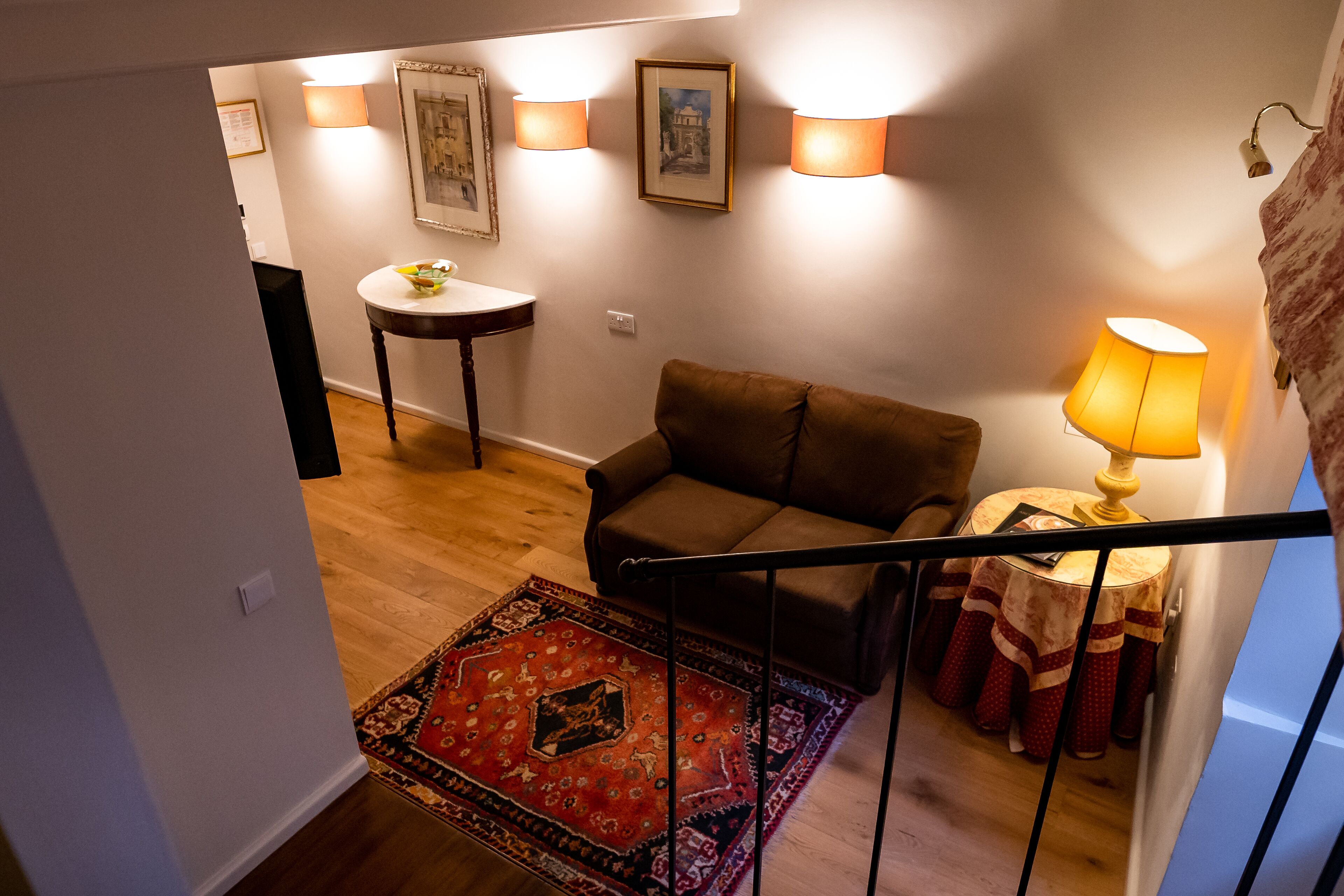 A staircase leading to a living area with a sofa, a small table, and a lamp.