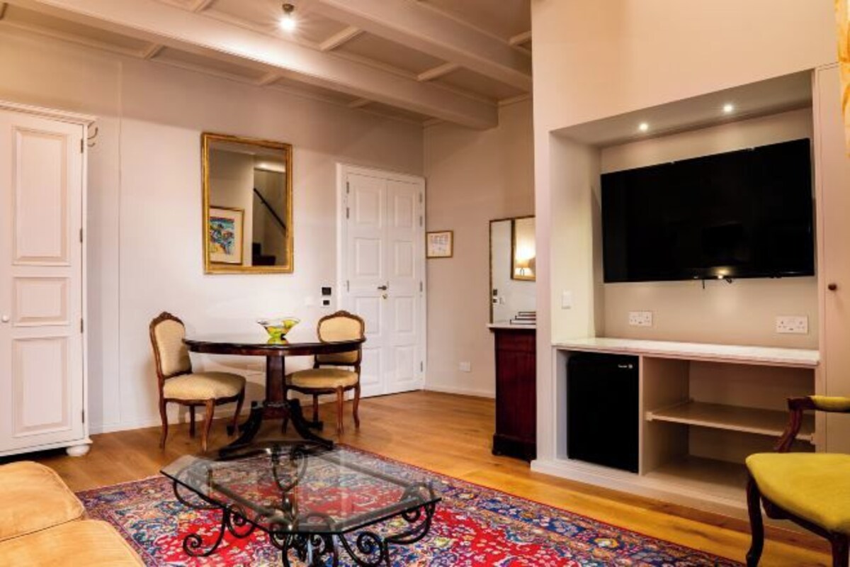 Una sala de estar con una mesa de comedor, sillas, una mesa de centro de vidrio, un televisor y una chimenea.