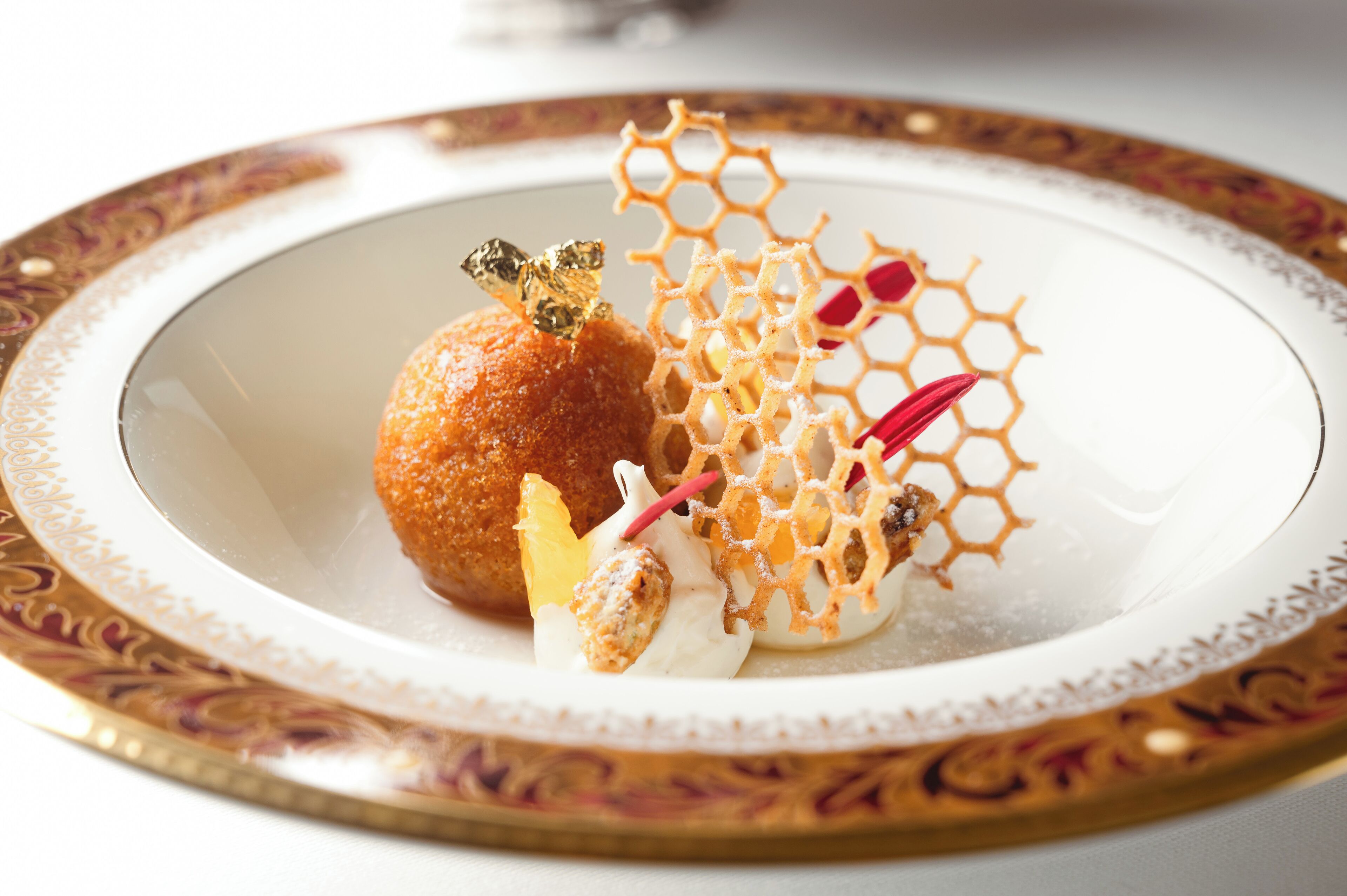Une assiette à dessert comportant un élément sphérique, une structure en forme de nid d’abeilles et un élément décoratif.