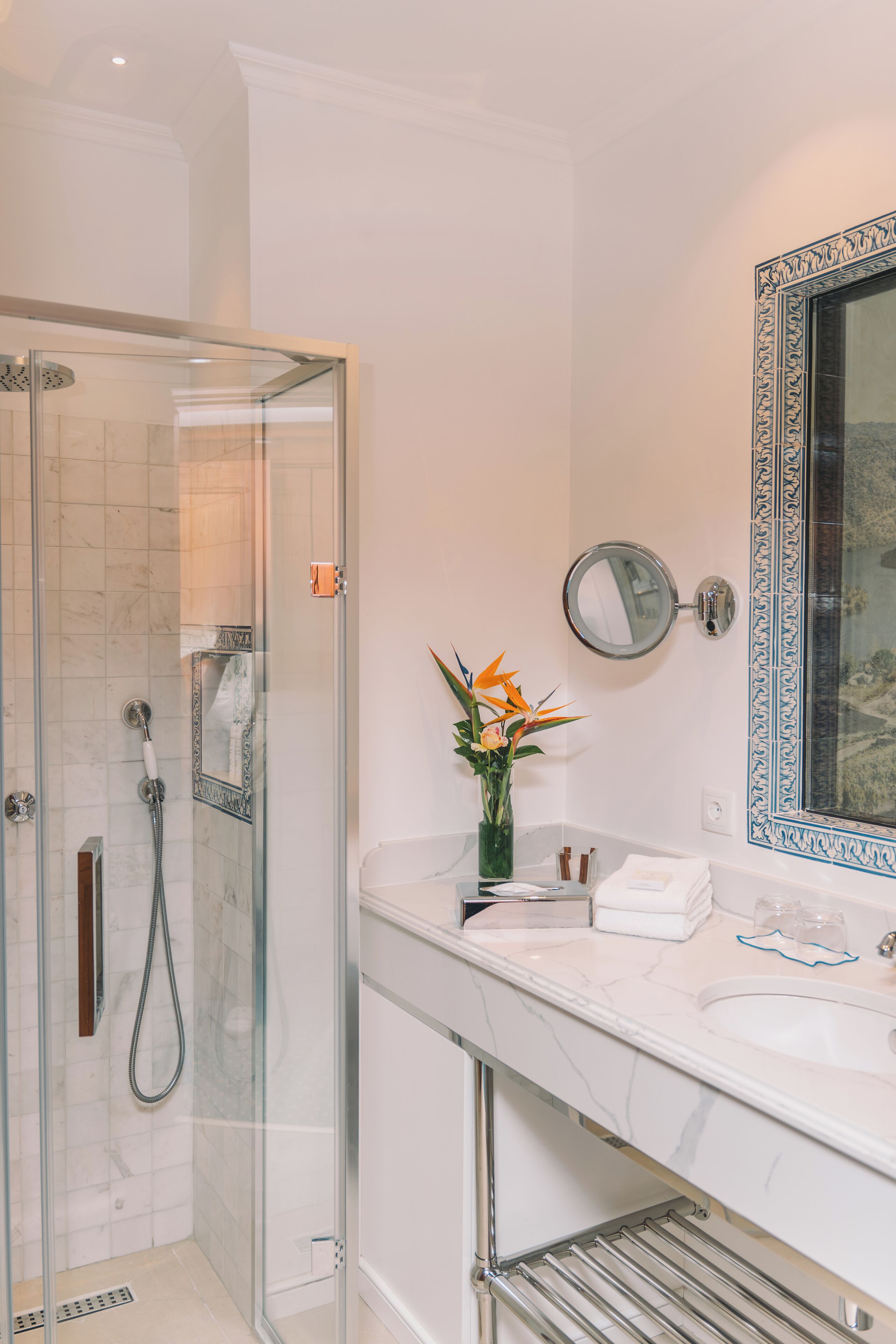 Une salle de bain moderne dotée d’une douche à parois de verre, d’un lavabo en marbre et d’un miroir décoratif.