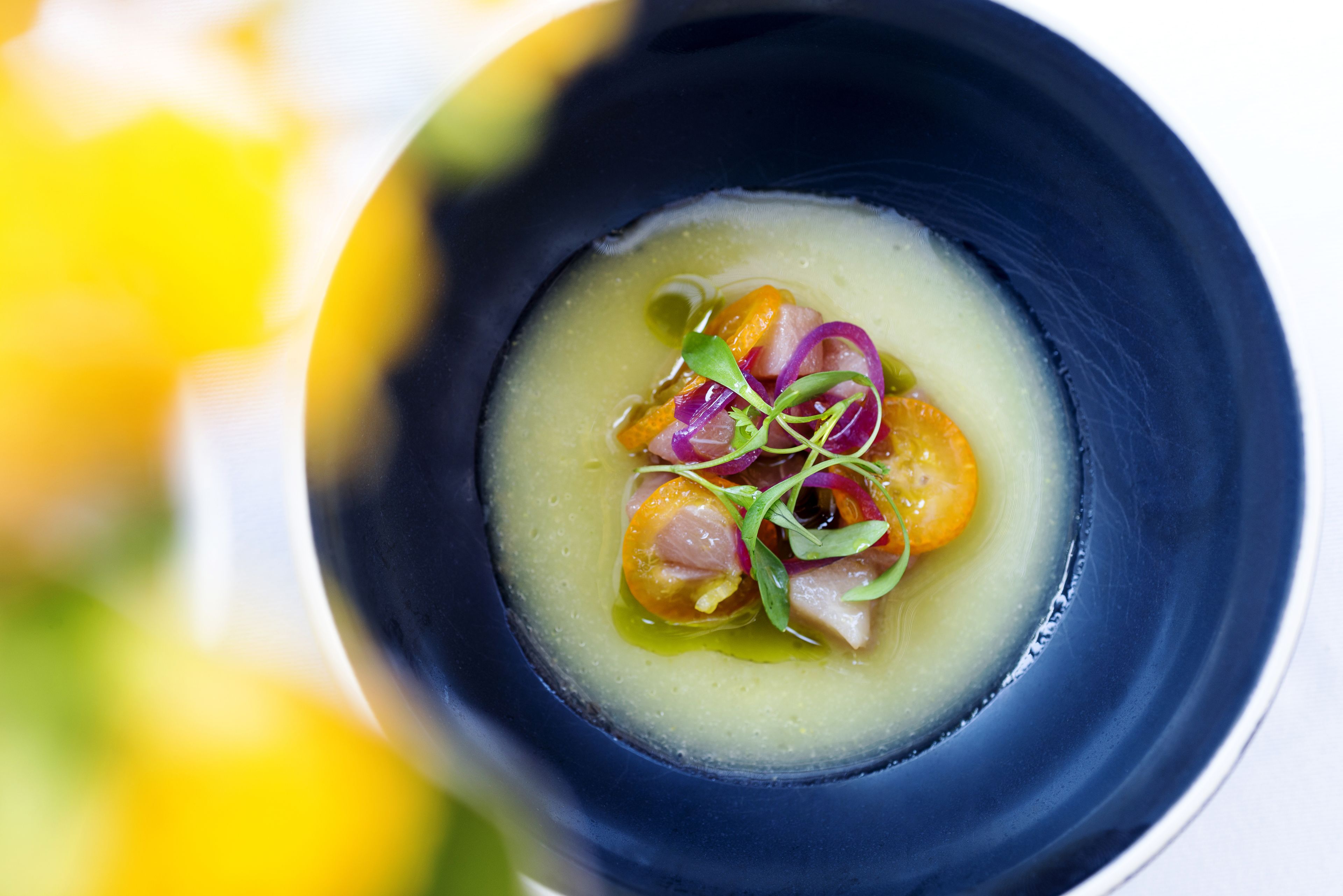 A bowl of soup with vegetables and herbs.