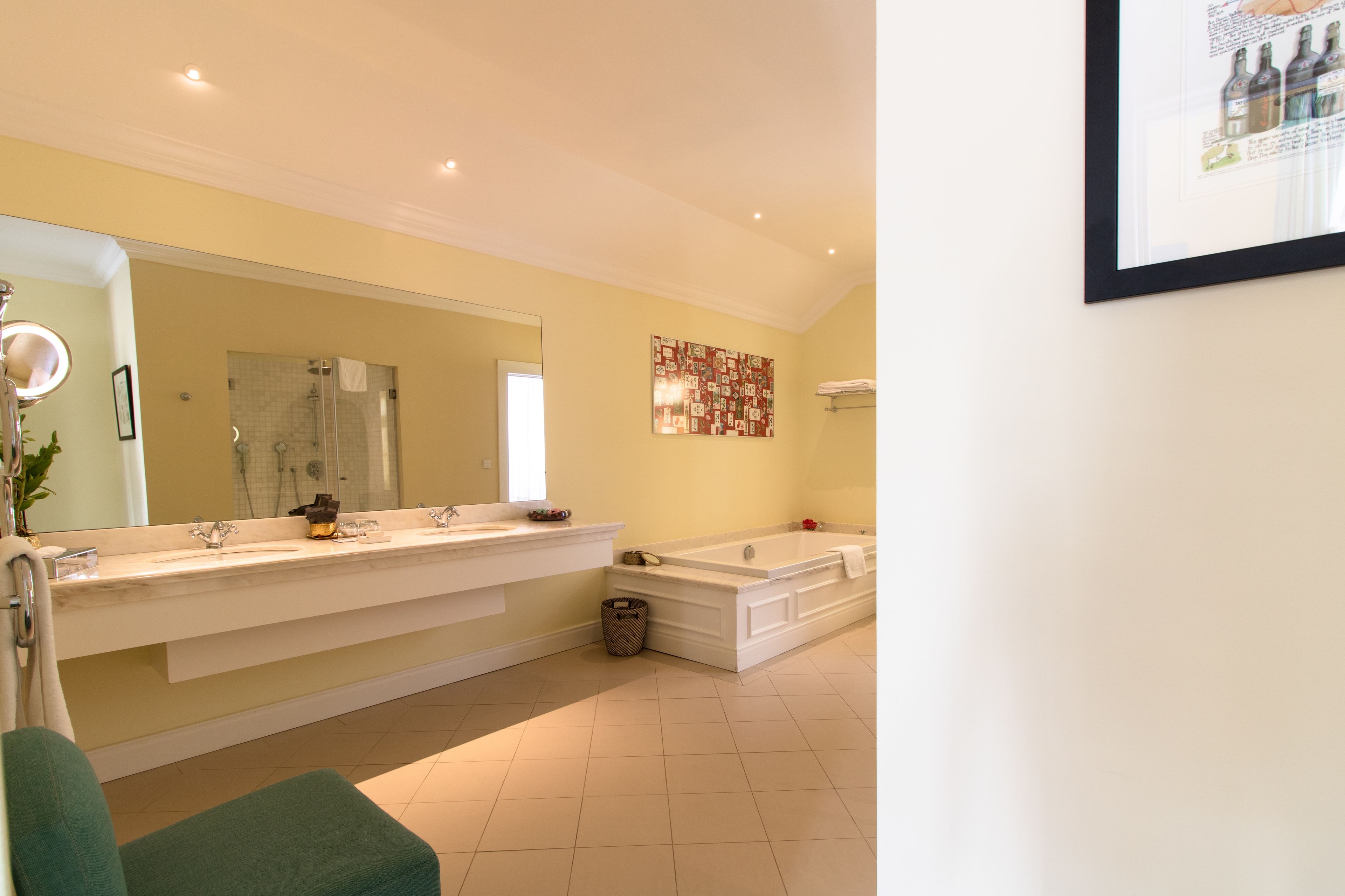 Un baño moderno con un espejo grande, dos lavamanos, una bañera y un cubo de basura.