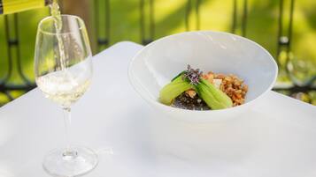 Una mesa blanca con un bol de comida y una copa de vino.