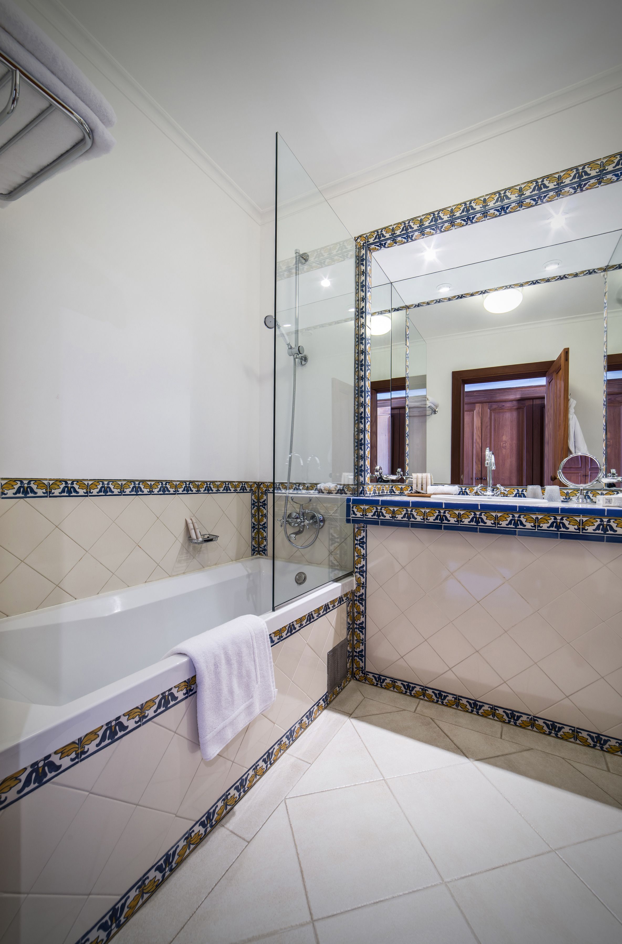 Un baño con bañera, cabina de ducha de vidrio y un espejo grande con marco decorativo.