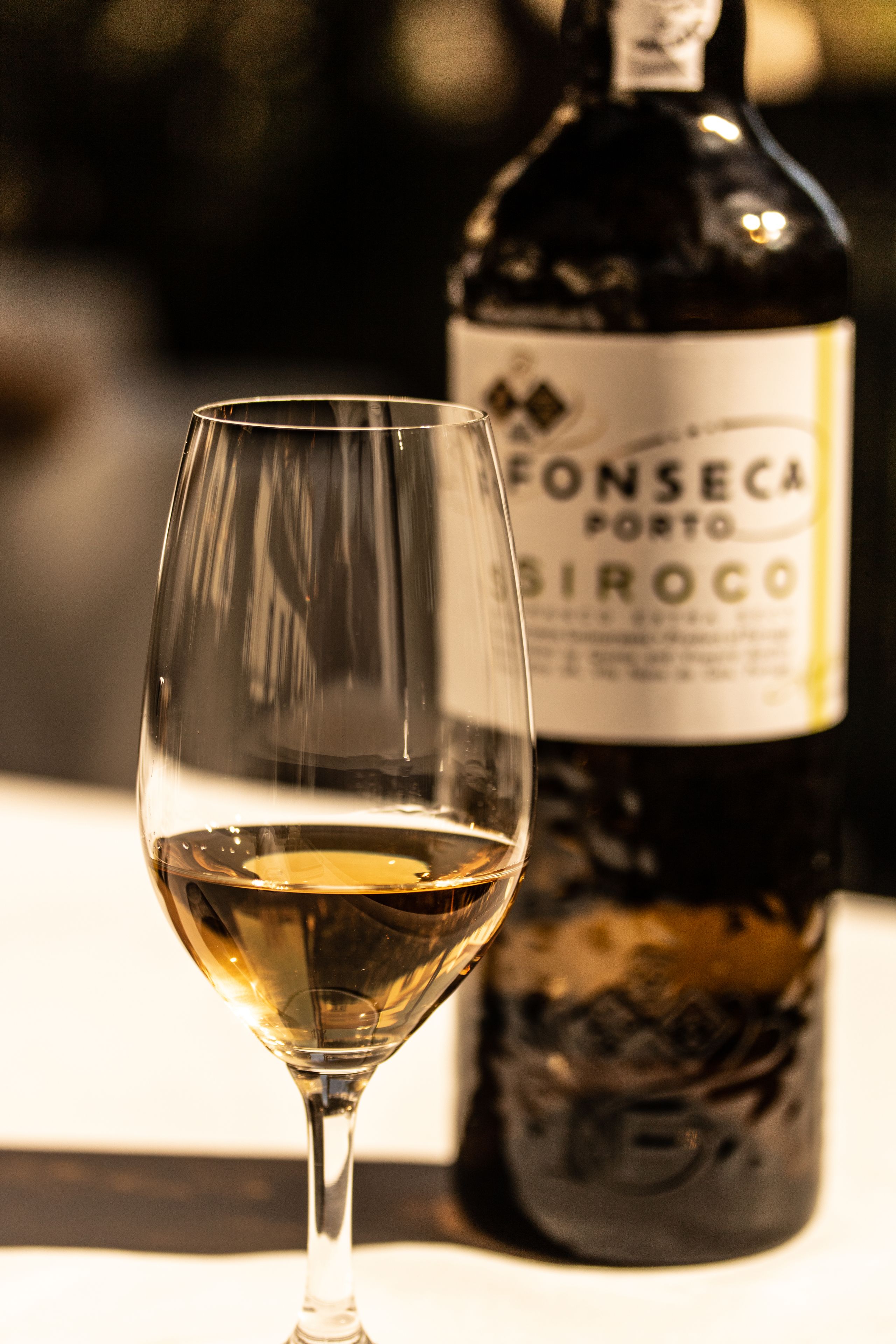 A wine glass with a bottle of Fonseca Porto Sirocco in the background.