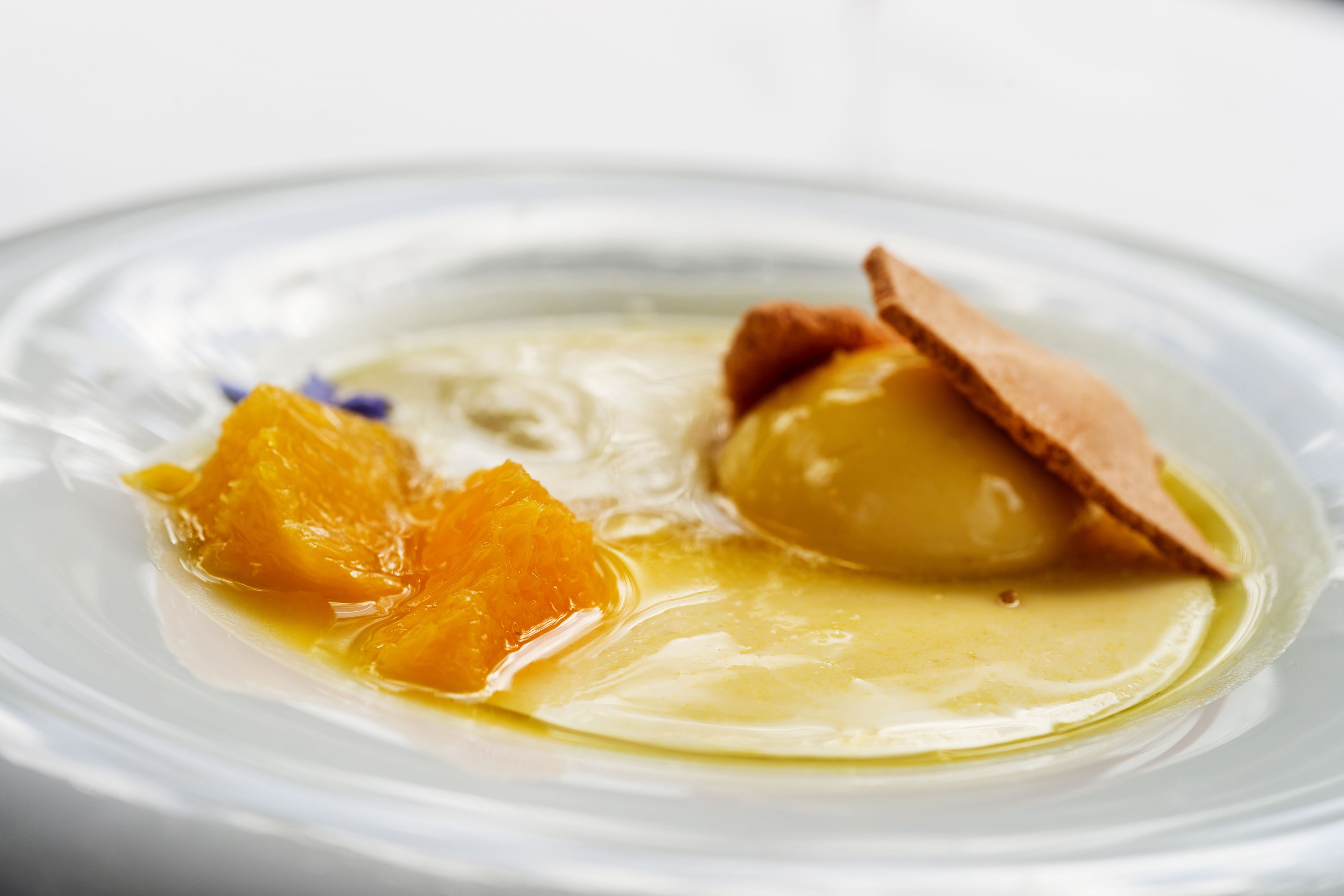 A dessert with a smooth, creamy texture and a slice of orange on a white plate.