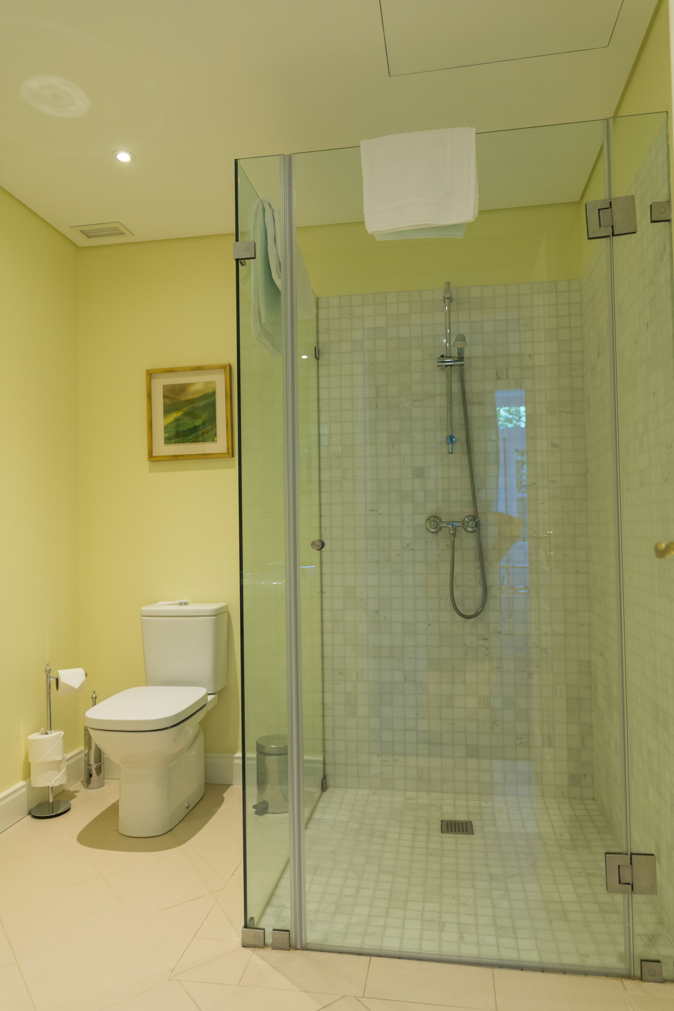 A bathroom with a glass-enclosed shower, a toilet, and a sink.
