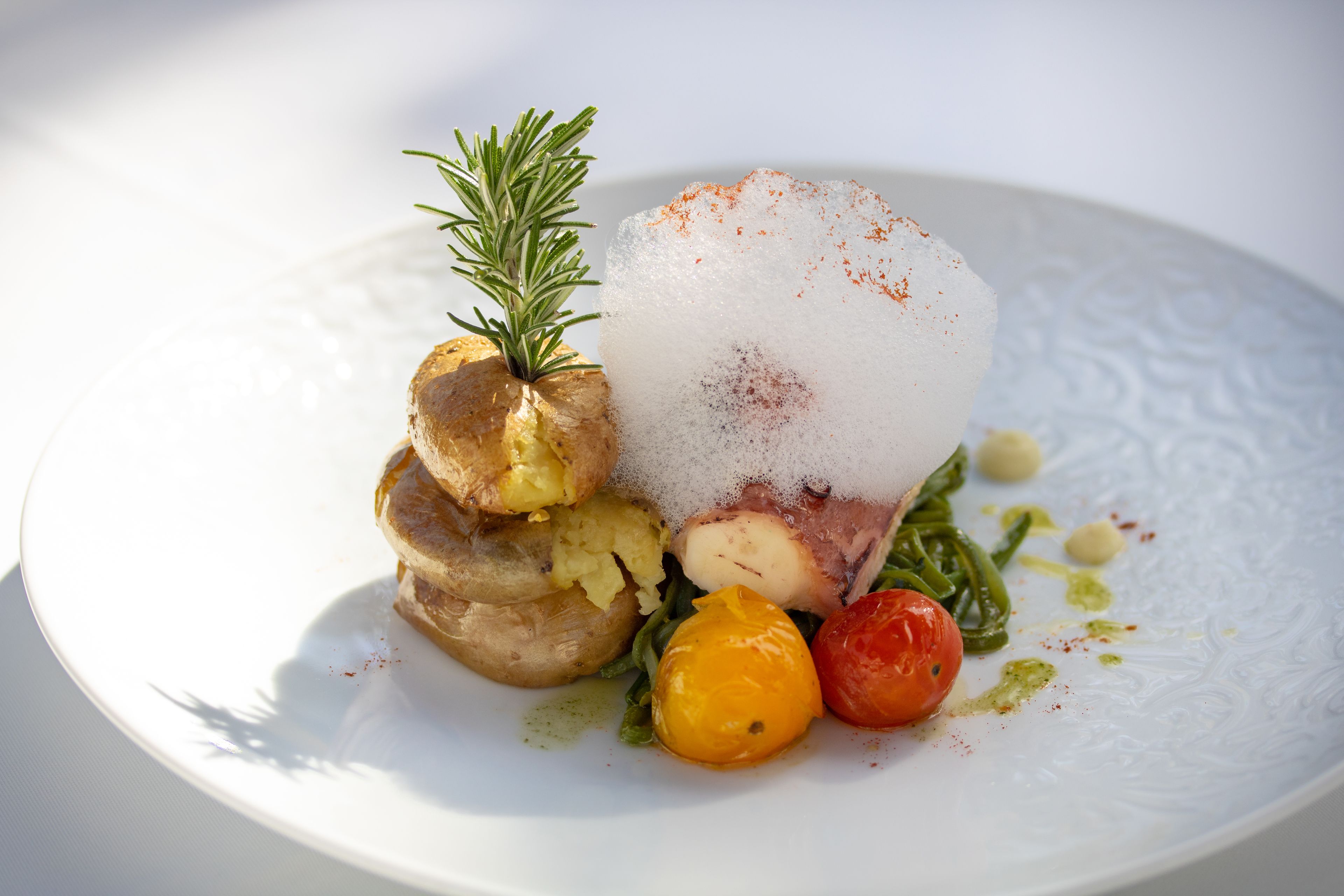Une assiette contenant un plat composé d’une pomme de terre, d’un morceau de viande et de quelques légumes.