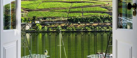 A room with a view of terraced vineyards and a body of water.