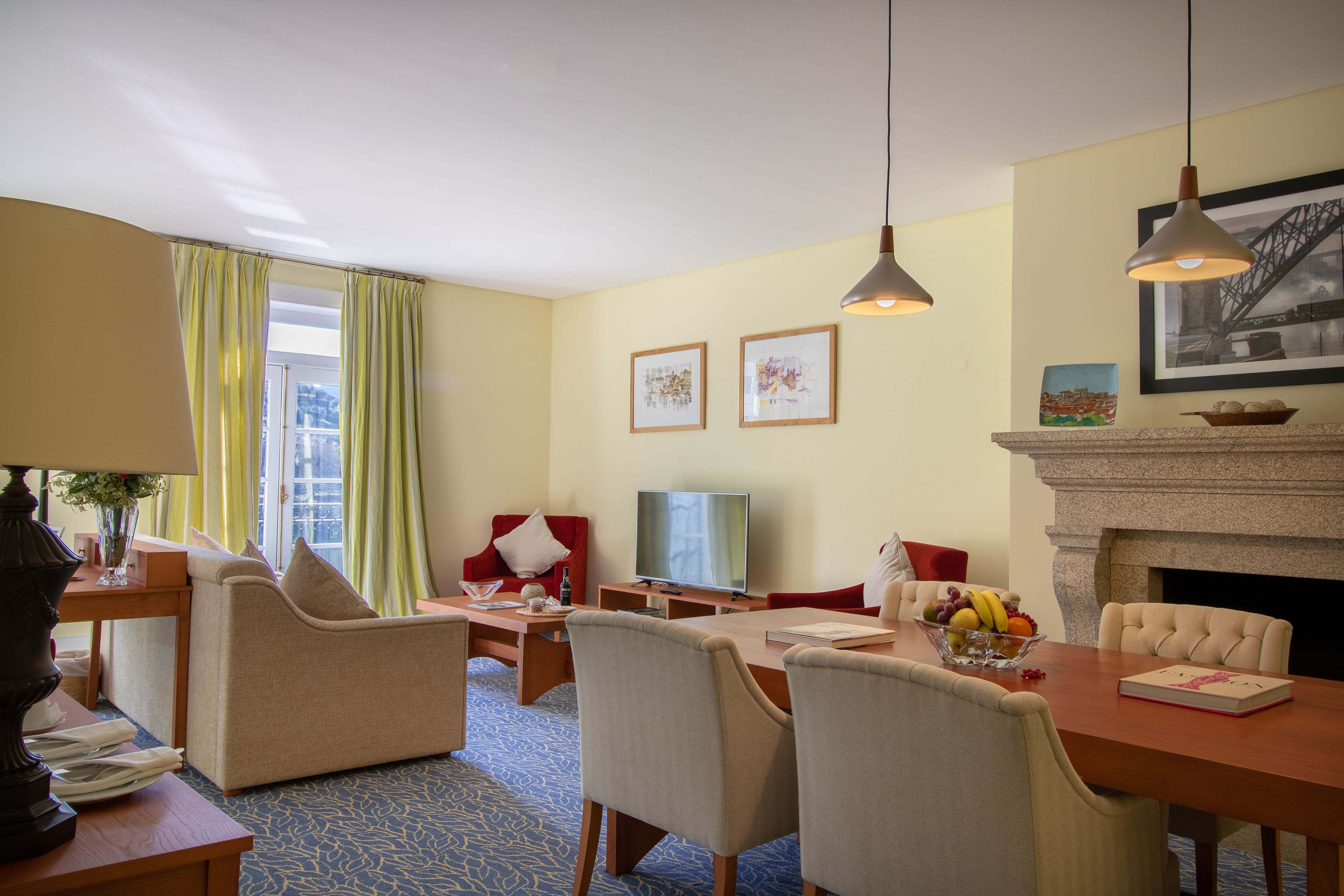 Quarto de hotel com área de refeições, sofá, televisão e lareira.