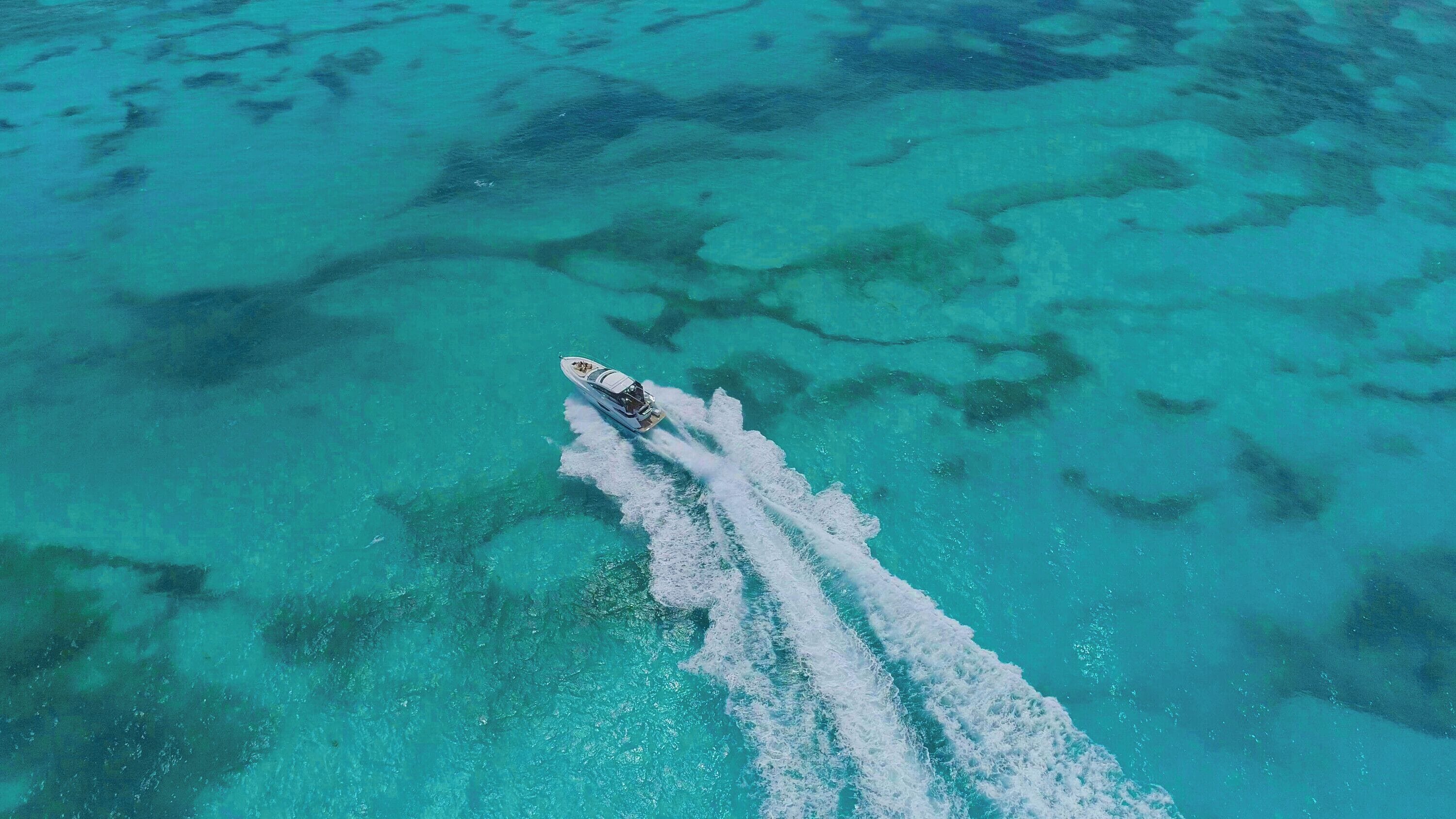 A boat creating a wake in clear turquoise waters.