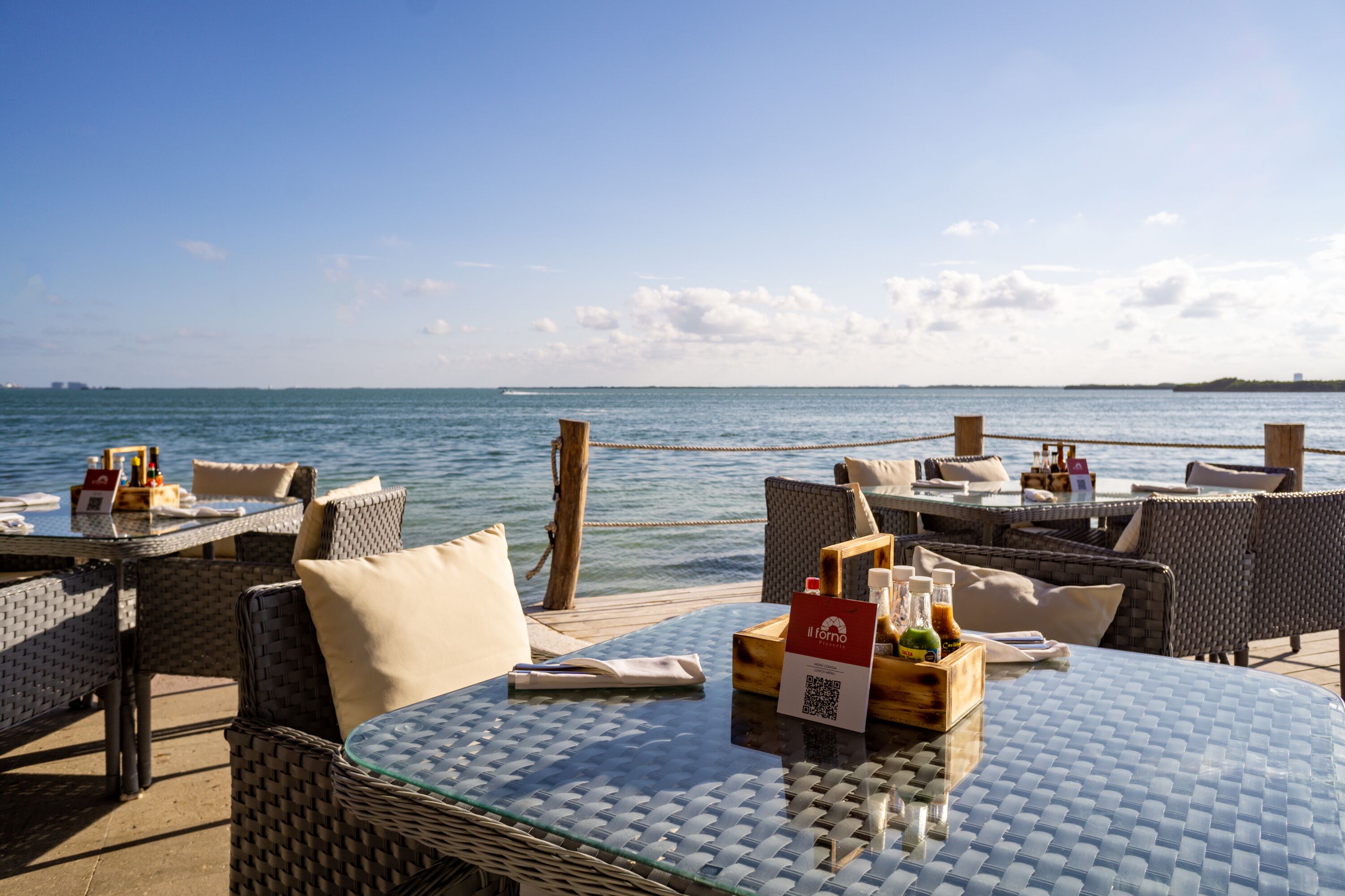 Een restaurant aan zee met terras, tafels en stoelen, met uitzicht op de oceaan.