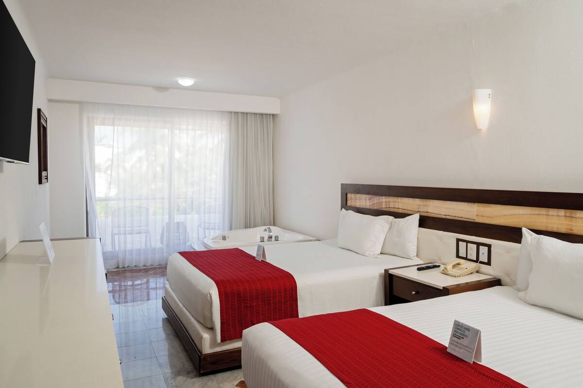 Ein Hotelzimmer mit zwei Betten, einem Schreibtisch, einem Telefon und einem Fenster mit Vorhängen.
