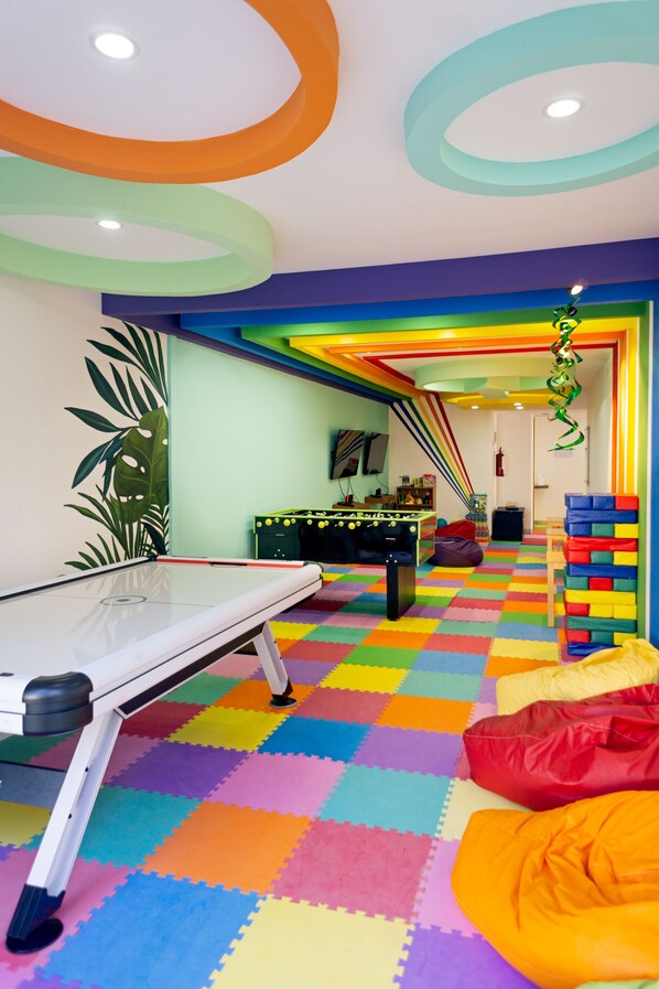 Une salle de jeux colorée avec un baby-foot, des fauteuils en forme de sac et un autre baby-foot.