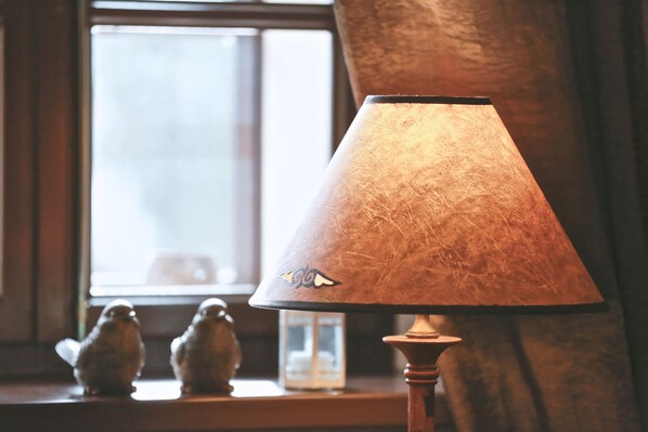 Een lamp met een structuurbezet kapje en een klein vogelmotief.