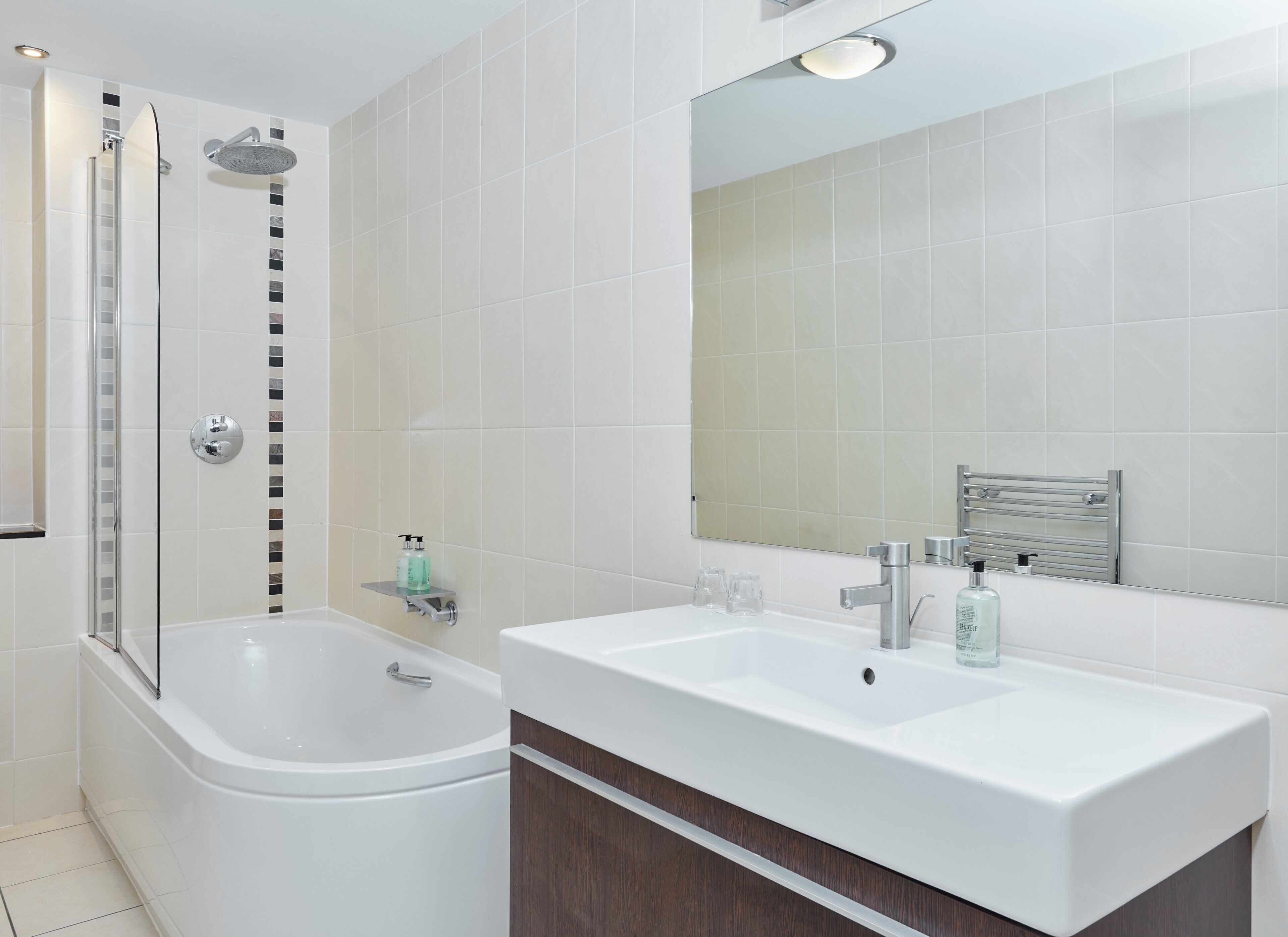 Une salle de bain moderne dotée d’une douche à parois de verre, d’une baignoire sur pieds et d’un meuble-lavabo avec un miroir.