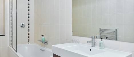Une salle de bain moderne dotée d’une douche à parois de verre, d’une baignoire sur pieds et d’un meuble-lavabo avec un miroir.
