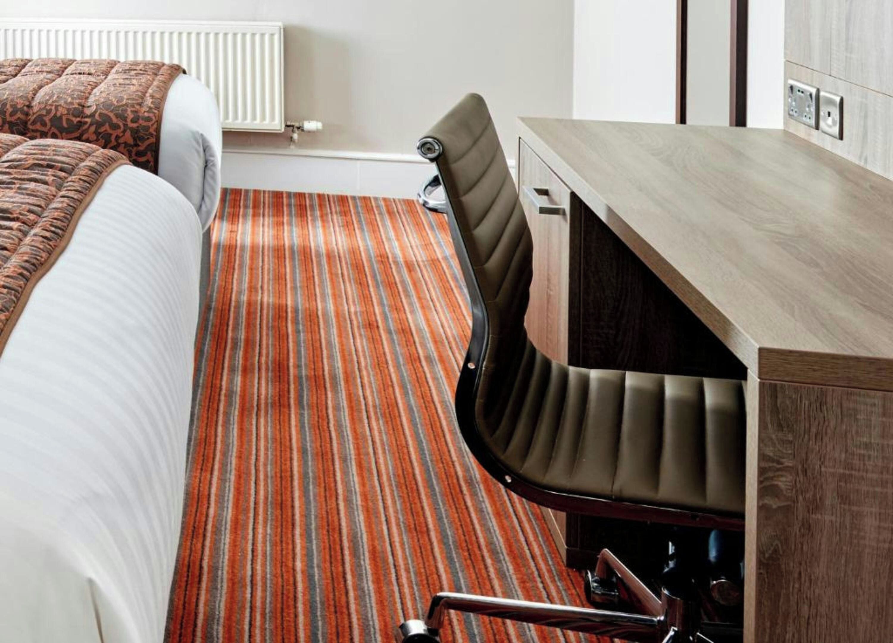 A hotel room with a bed, a desk, and a chair.