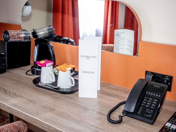 A hotel room with a coffee maker, a tea kettle, a phone, and a welcome sign. - Mercure Thurrock Stifford Hall (Grays)