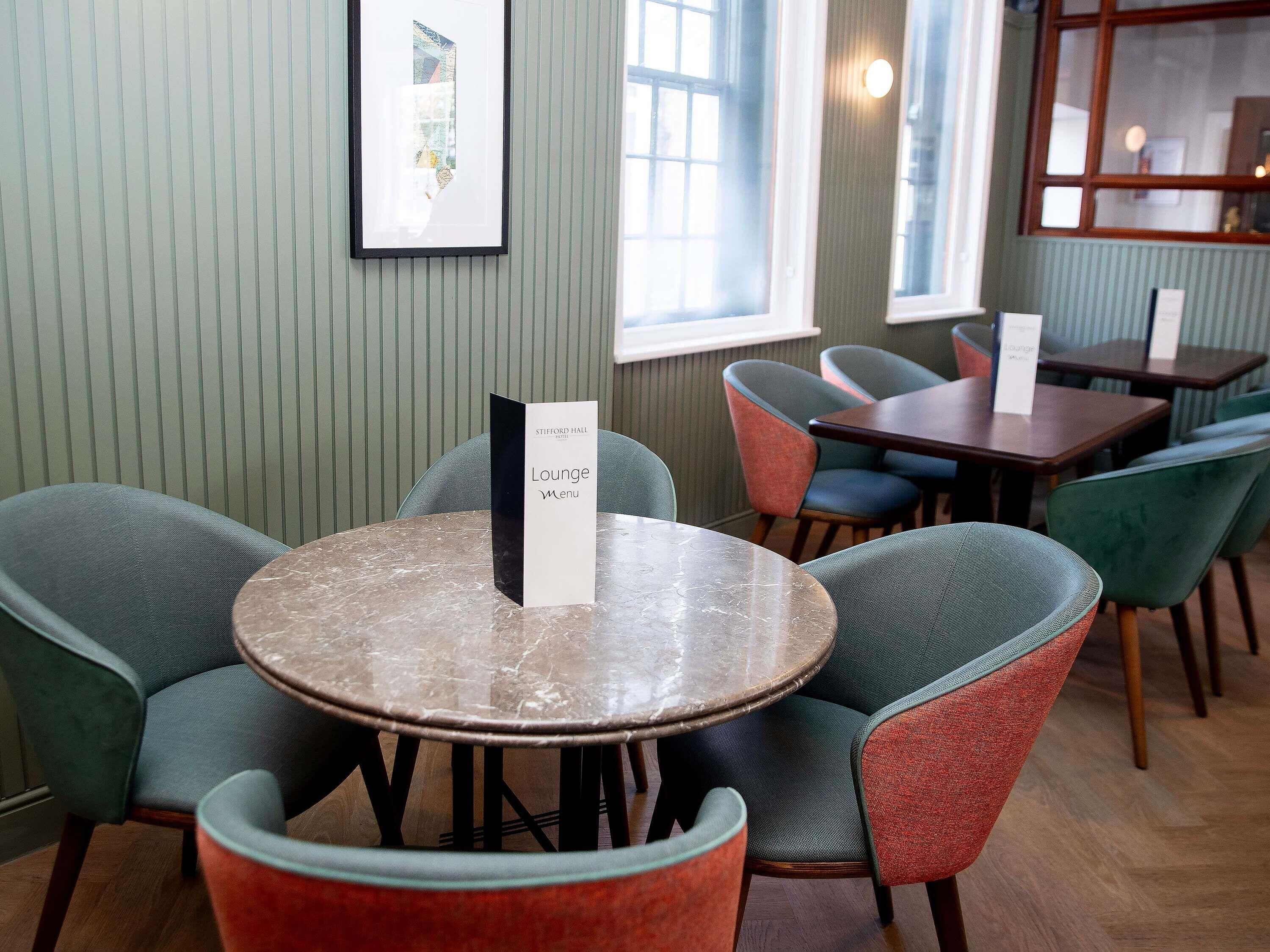 A dining area with round tables and chairs, a menu stand, and a framed picture on the wall.