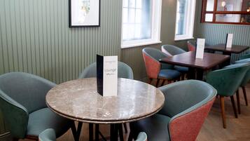 A dining area with round tables and chairs, a menu stand, and a framed picture on the wall.