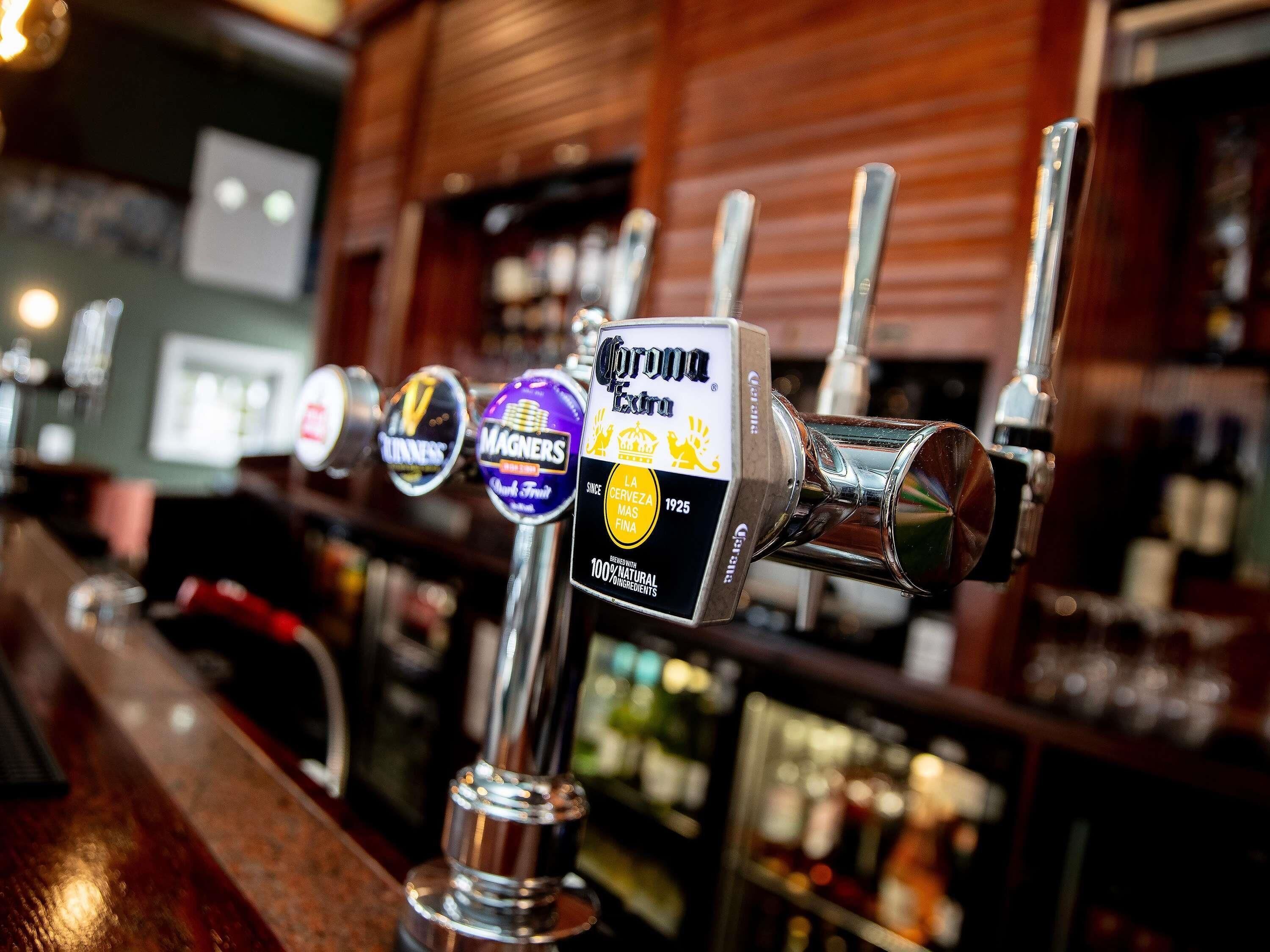 Een bar met meerdere biertaps, waaronder Corona Extra en Magners.