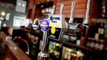 Een bar met meerdere biertaps, waaronder Corona Extra en Magners.