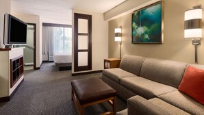 A hotel room with a sofa, a TV, a painting, and a lamp. - Hyatt Place Baltimore/Owings Mills (Owings Mills)